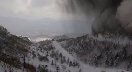A black cloud moving in from the top right corner of the frame following a volcanic eruption nearby and a near-simultaneous avalanche, near Mount Kusatsu-Shirane.