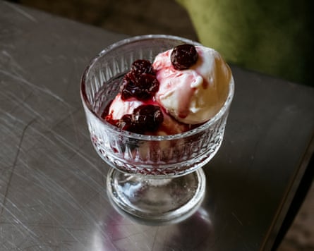 a glass dish of ice-cream with sour cherries and a dark-red preserve
