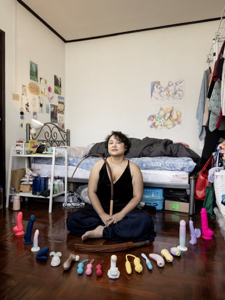 Photograph of Coco sat with cross legs and her sex toys arranged in a semicircle on the floor in front of her