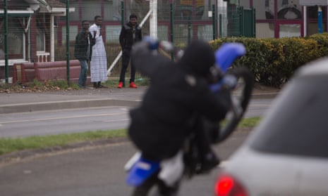 Teenagers in the Parisian suburb of Argenteuil watch a dirt bike rider pull a wheelie