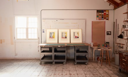 Three framed works on a makeshift workbench in a room with bare walls and floorboards
