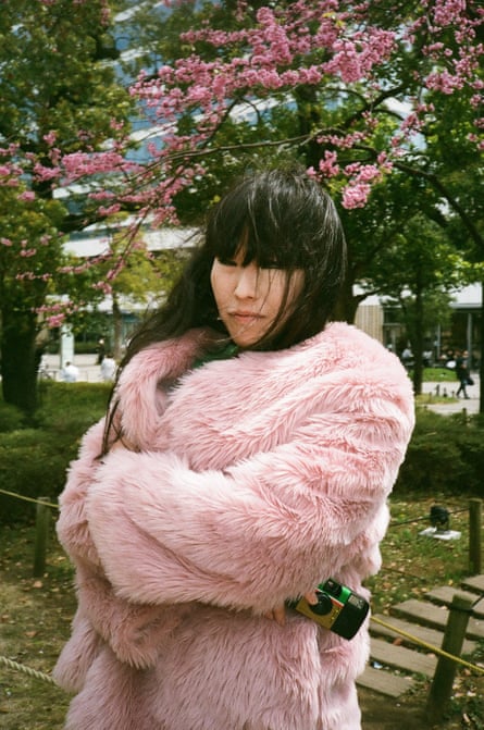 Japanese photographer Hiromix in a pink fur coat against cherry blossom in a Tokyo street
