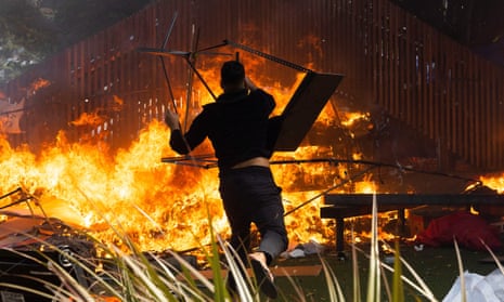 A man throws a desk onto a fire that rages on the grounds in front of Parliament