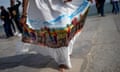 A woman holds out the skirt of her white dress showing the printed scene of slaves picking cotton on Lisbon’s Praça do Comércio.