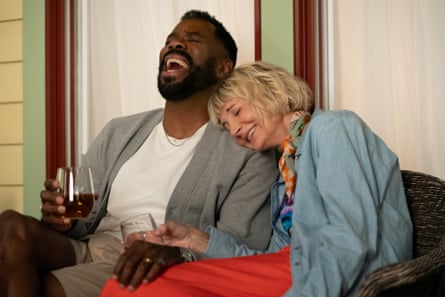 A man and a woman sitting on a chair with glasses of wine, laughing