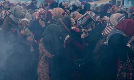 Women cower from tear gas while protesting about the government takeover of Zaman in Istanbul. 