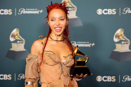 FKA twigs, whose hair is red, holding up her Grammy on the red carpet