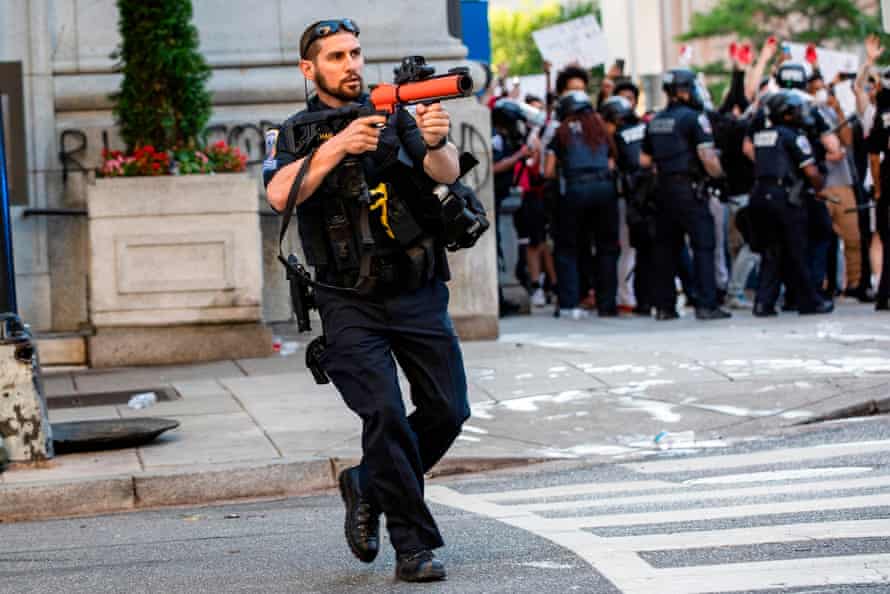 A police officer aims a non-lethal launcher at protesters as they clash in Washington DC on 31 May.
