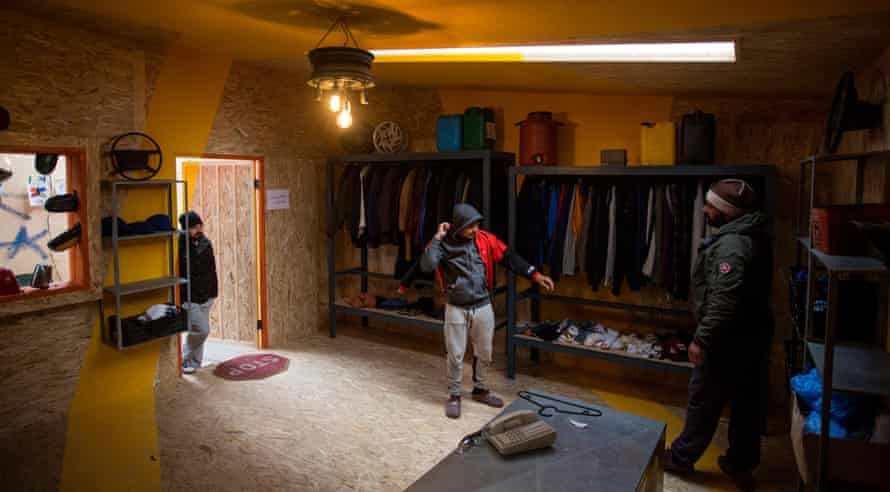 Refugees try on clothes in the men's clothing store at the Katsikas refugee camp in Greece