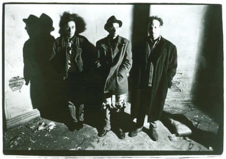 Steve Albini with the two other members of Big Black, in overcoats, stand against a wall in around 1986