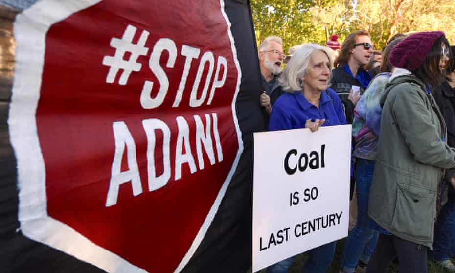 Protesters in Canberra hold banners against Adani