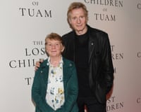 Catherine Corless and Liam Neeson pose together in front of an event backdrop