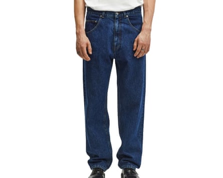 A cropped at waist image of a model wearing A Day’s March dark blue jeans and brown shoes