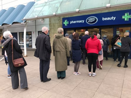 People queue outside a Boots pharmacy store in west London where stocks of hand sanitiser are limited to two per person.