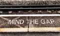 "PERHATIKAN KESENJANGANNYA" ditulis di tepi peron kereta api