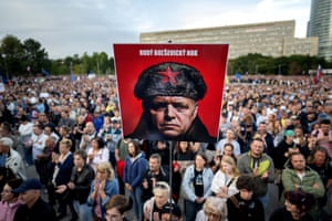 A placard depicting Robert Fico reading ‘Enough Red Bolshevik’ is held up by protesters