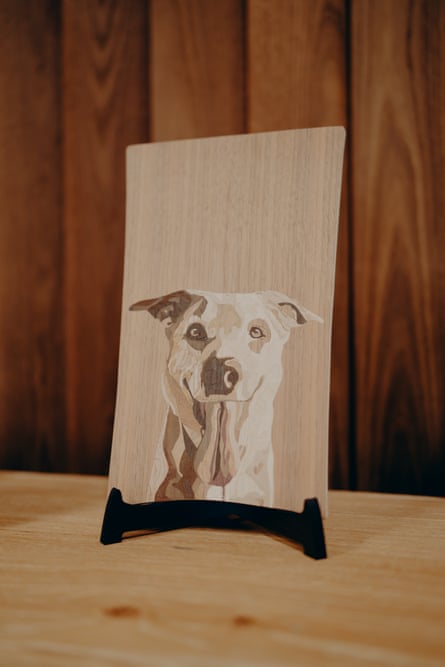 A wood car panel engraved with a customer’s pet dog portrait stands on a display stand
