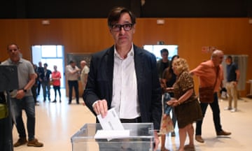 Salvador Illa, wearing glasses, a dark jacket and white shirt, inserts a voting slip into a ballot box