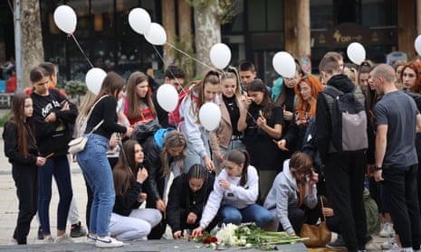 Students leave flowers and light candles and hold white balloons in Serbia