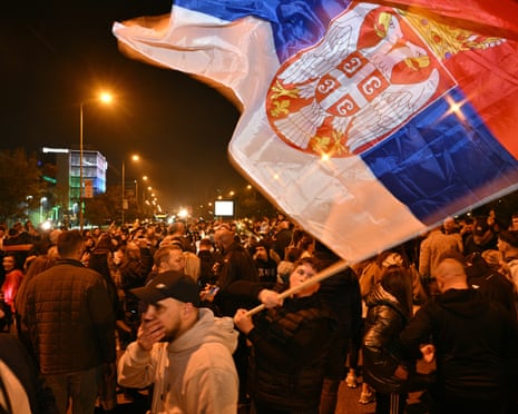 Celebrating supporters in Belgrade gather as a boy waves a huge Serbian flag at night