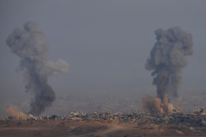Two smoke plumes rise amid the rubble of destroyed structures