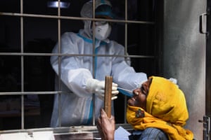A health worker collects a swab sample from a resident to test for coronavirus at an experimental center in New Delhi