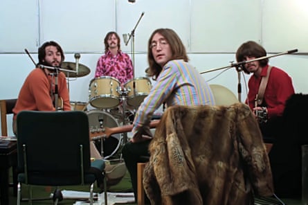 The Beatles sit on chairs with guitars in a recording studio
