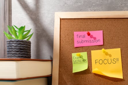 A student’s workspace featuring a corkboard with colorful reminder notes and a stack of books.