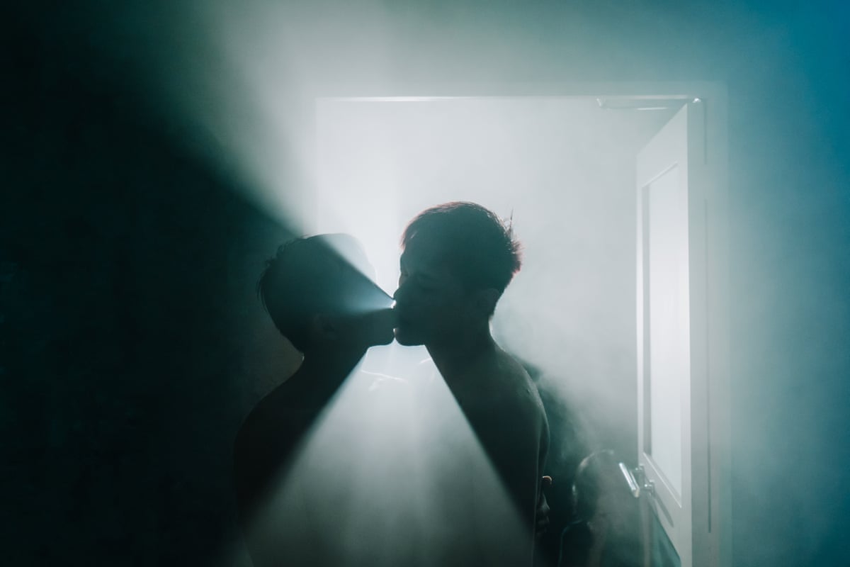 Two figures are silhouetted against lit mist as they appear to lean in for a kiss