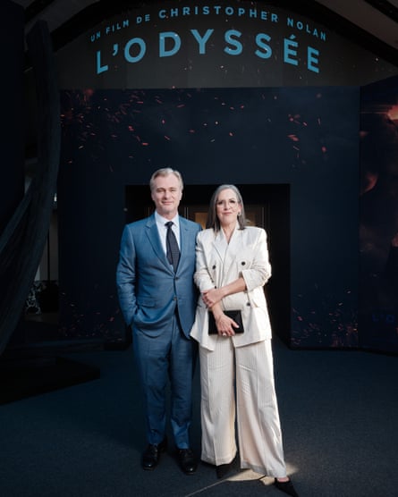 Christopher Nolan in a blue suit, light blue shirt and dark blue tie and Emma Thomas in a cream flowing trouser suit attend The Odyssey premiere in Paris.