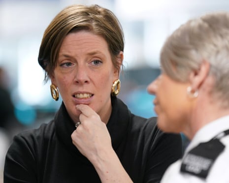 Phillips, finger on chin, in conversation with female police officer