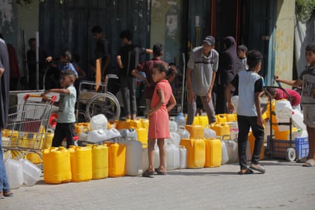 Children wait to fill water bottles at a distribution point in the Nuseirat refugee camp in Gaza.