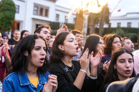 A group of young people clap and chant.
