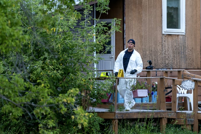 A police officer in protective gear works at the scene of a stabbing.
