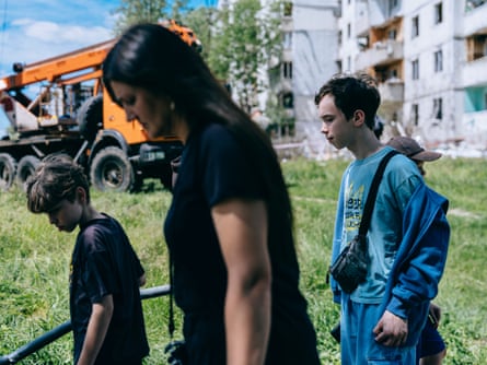A woman and two young boys walk past a recovery vehicle