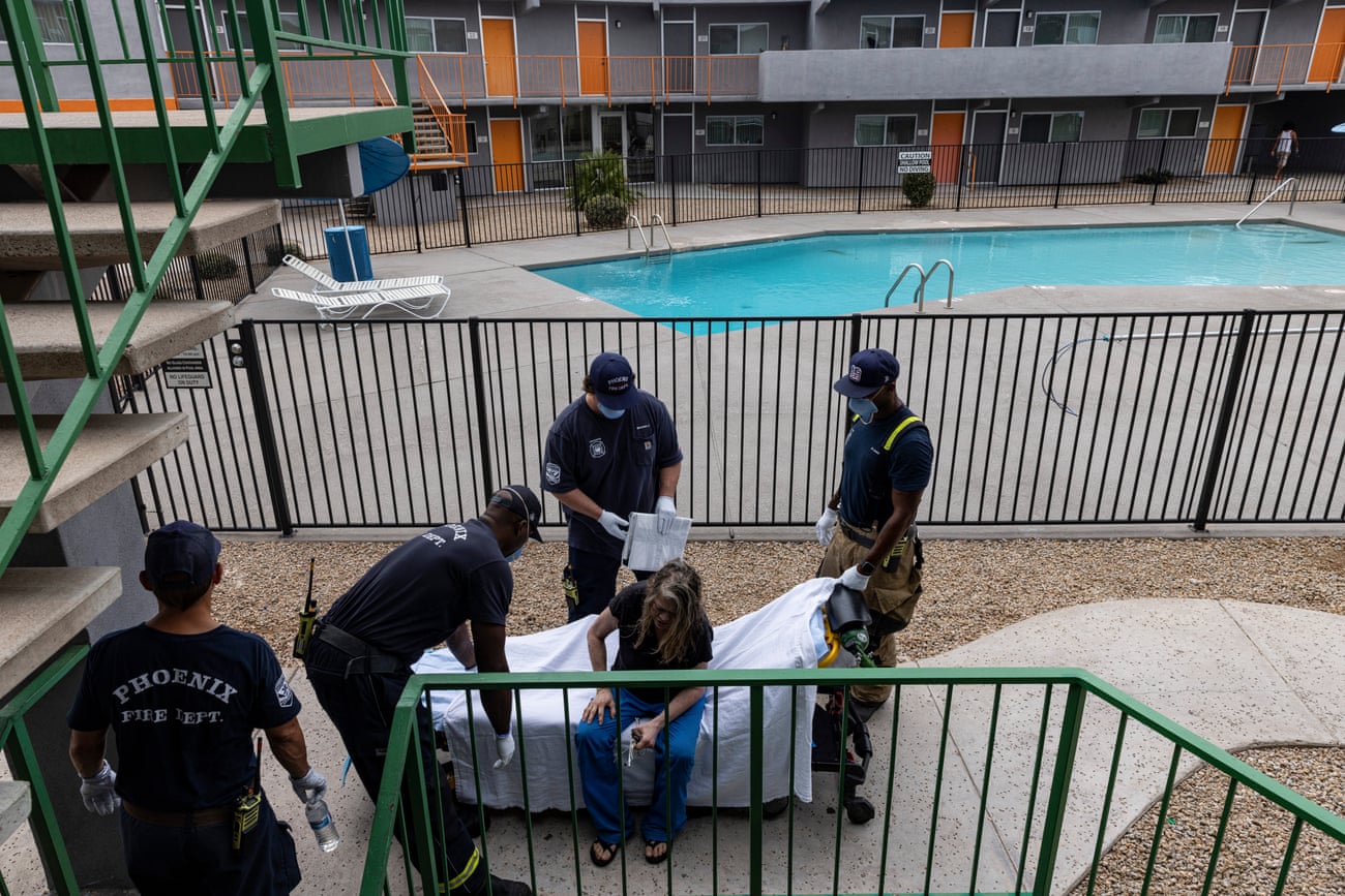 Paramedics attend to a woman on a white stretcher by a pool