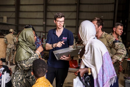 Ministry of Defence handout photo of a Foreign and Commonwealth Rapid Response team member helping evacuees before they fly to Cyprus from Wadi Seidna airport in Khartoum, Sudan.