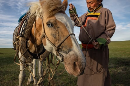 A Buryat herder stands next to a horse
