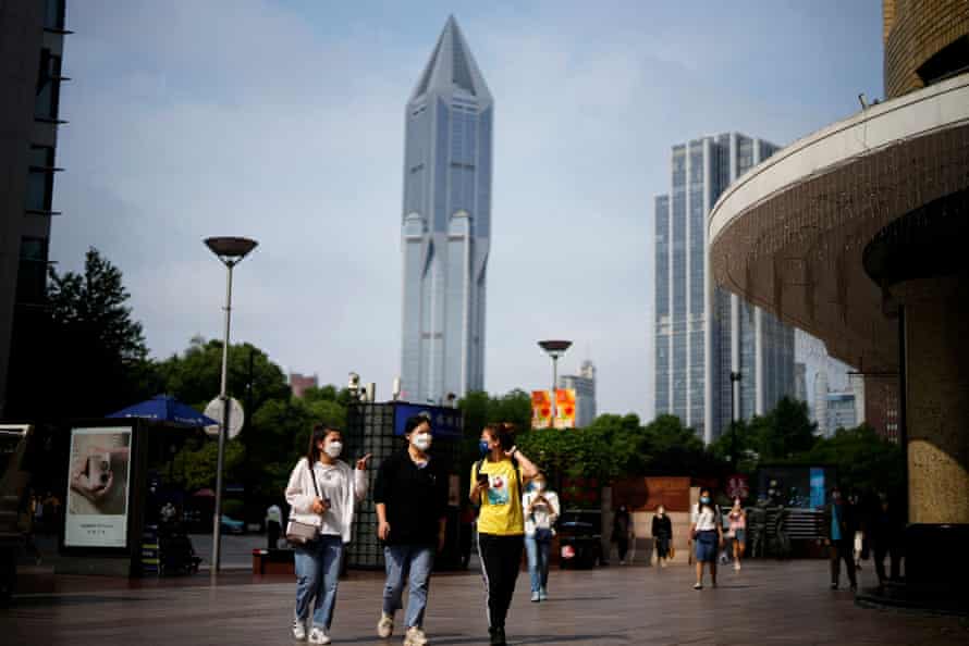 People wearing face masks walk on a street in Shanghai today