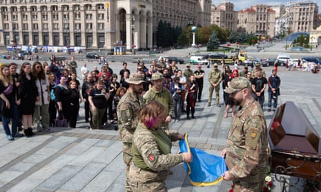 Army personnel fold a Ukrainian flag at the funeral of Daria Filipieva 