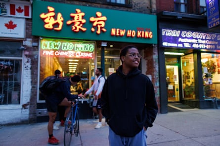 A young man grins in front of a Chinese restaurant.