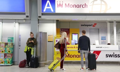 Would-be passengers stand at an empty Monarch service desk at the Luton airport