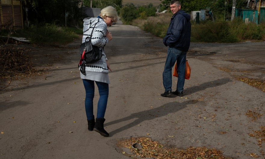 Yulia et Yuriy Postol examinent un morceau de missile russe encastré dans la route alors qu'ils marchent vers leur domicile à Slatyane.