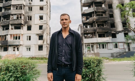 Andriy Shevchenko pictured in Borodyanka, a town about 40 miles north of Kyiv, with the results of Russian bombing visible in the flats behind him