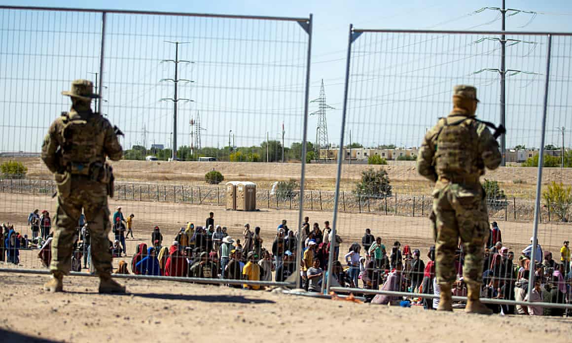 Migrants wait in line adjacent to the border fence to enter into El Paso, Texas, on 10 May.