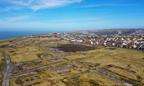 An aerial shot showing a large expanse of flat brownfield land on the Cumbrian coast