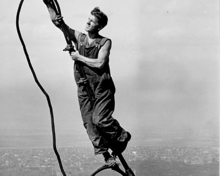 A construction worker connects two cables suspended high above the New York during the construction of the Empire State Building.