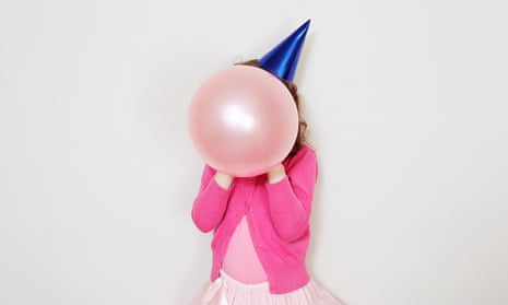 A girl holding pink balloon in front of her face