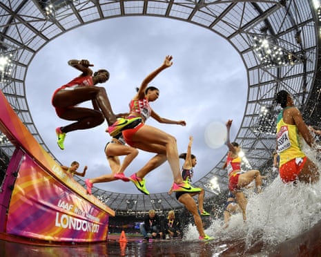 Runners Tigest Getent and Fadwa Sidi Madane leap a hurdle into the water jump during a steeplechase heat.