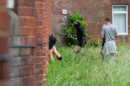 Five young people stand in long grass outside the hotel. Two appear to be leaning into an open window